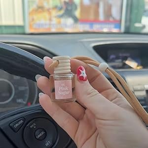 photo of a person holding a pink sugar car freshener in their car