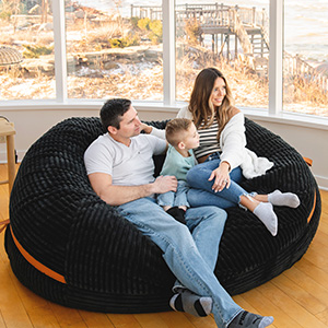 Family of man, boy and woman sitting on large black bean bag chair