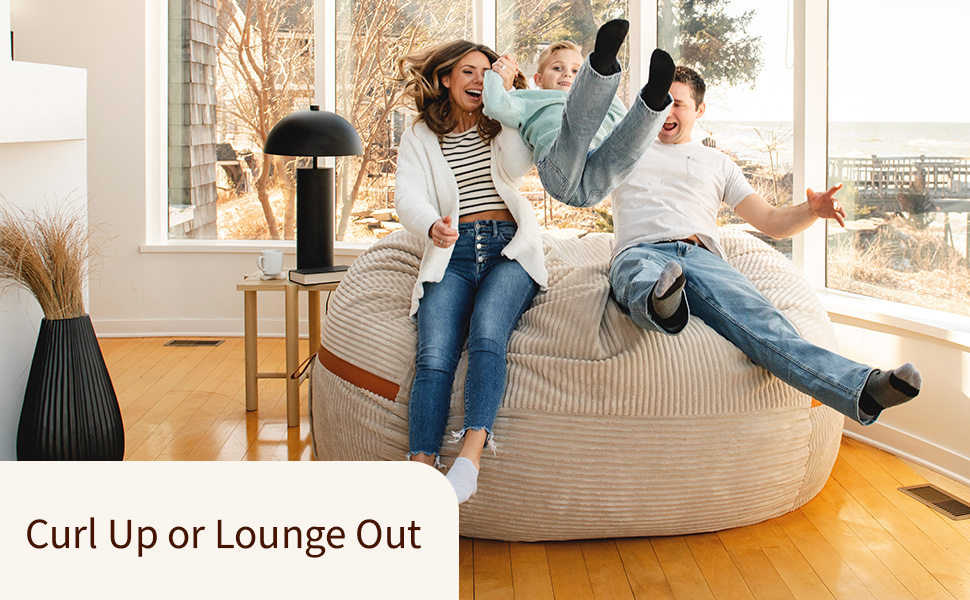 Family enjoying a cozy beige bean bag in a sunny room with modern decor and large windows.