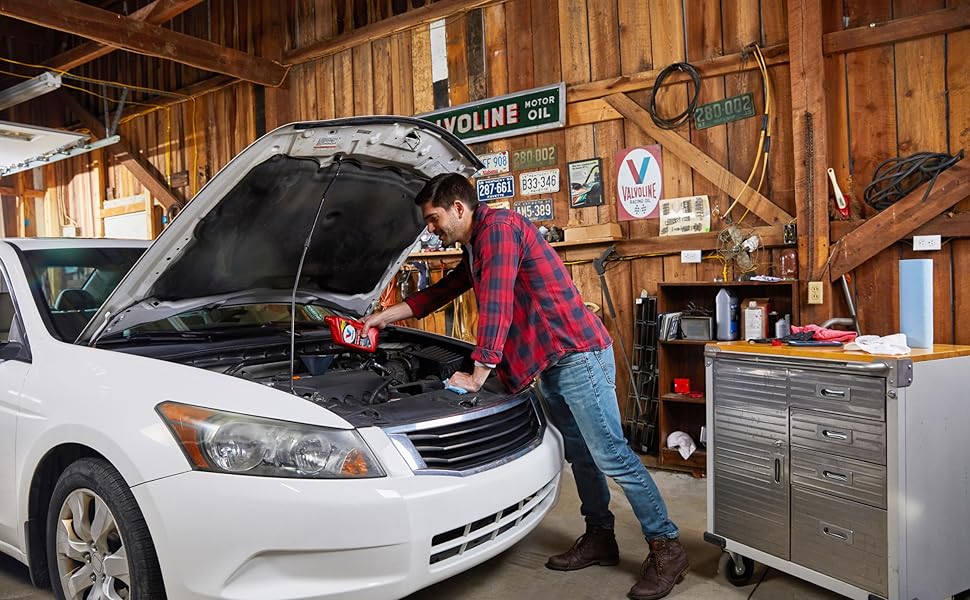 Man using valvoline high mileage in vehicle in garage