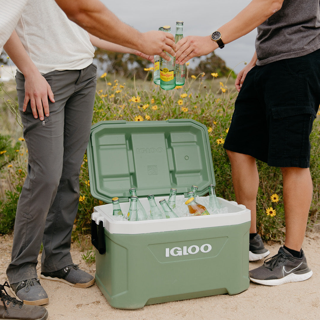 Two guys standing next to open 52 quart cooler with ice and drinks.
